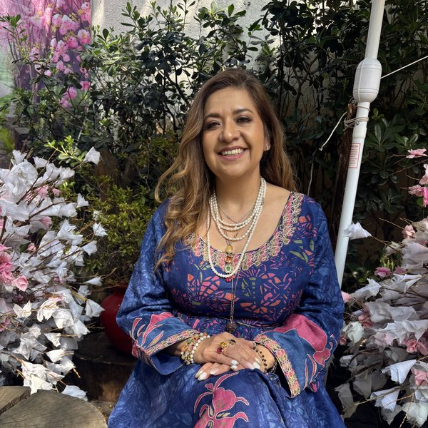 Cris smiling, sitting in a garden with her hands on her knees